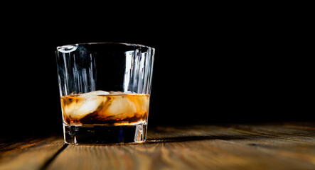 whiskey and ice on a wooden table dark background