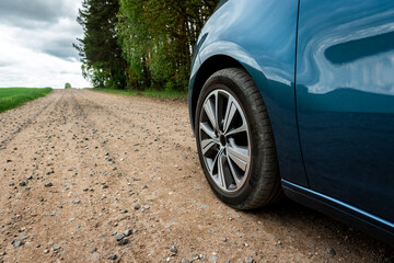 Fototapeta na wymiar Car tire on gravel road near field.
