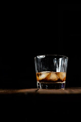 whiskey and ice on a wooden table dark background