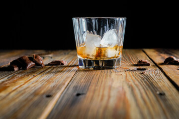 malt scotch whiskey with ice and chocolate on wooden table