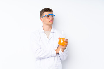 Fototapeta premium Young handsome man over isolated white background with a scientific test tube and looking lateral