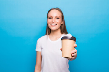 Portrait of a pretty young woman holding takeaway coffee cup isolated over blue background