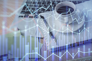 Double exposure of forex chart drawing and desktop with coffee and items on table background. Concept of financial market trading