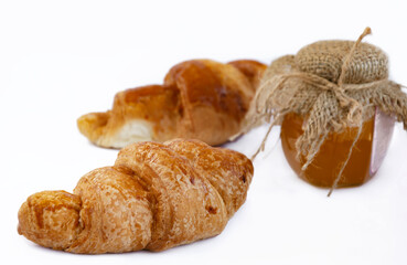 croissant with crispy crust and honey in a jar with burlap, on a white plate,
