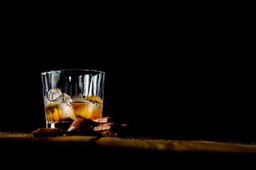 malt scotch whiskey with ice and chocolate on wooden table