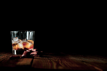malt scotch whiskey with ice and chocolate on wooden table