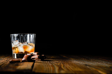 malt scotch whiskey with ice and chocolate on wooden table