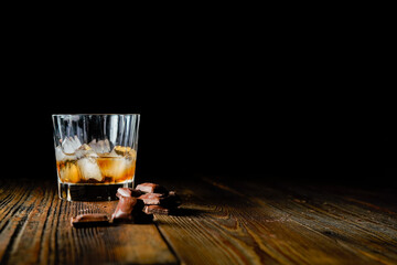 malt scotch whiskey with ice and chocolate on wooden table
