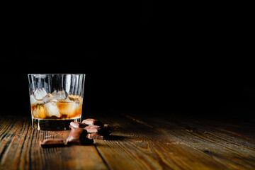 malt scotch whiskey with ice and chocolate on wooden table