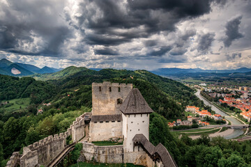 Famous landmark Celje castle towers with Celje town and hills covered with forest in background. Dramatic clouds in the sky. Slovenia landscape