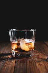 whiskey glass ice on the rock side view on wooden table dark background