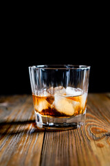 whiskey glass ice on the rock side view on wooden table dark background