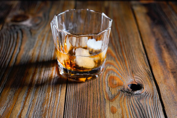 whiskey glass ice on the rock side view on wooden table