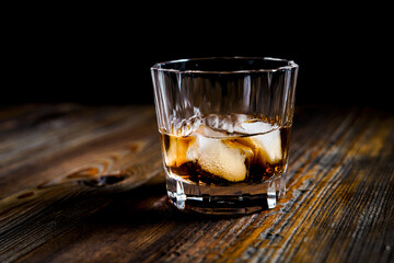 whiskey glass ice on the rock side view on wooden table dark background