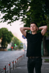Young adult man in a black t-shirt and jeans walks on a city street