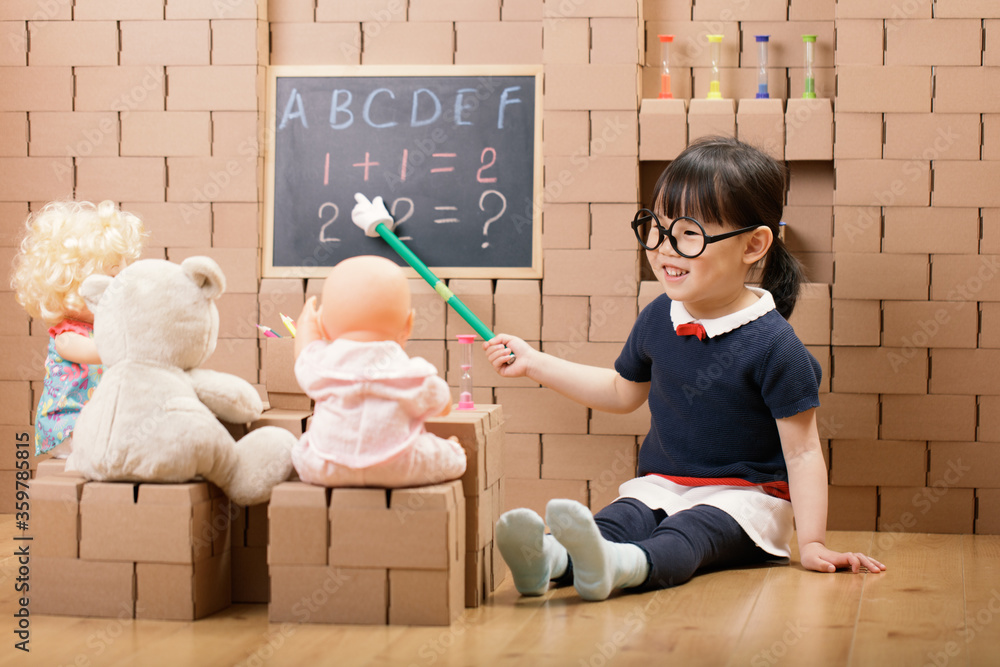 Wall mural toddler girl pretend play as a teacher at home