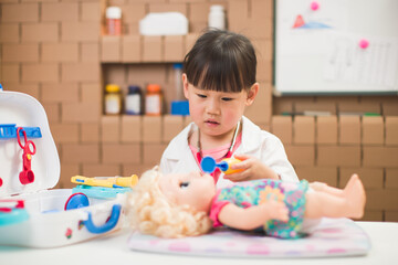 Fototapeta premium toddler girl pretend play doctor role at home