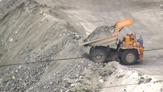 Tilt shift perspective of truck excavating in quarry. Mining operations.