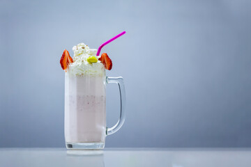 Milkshake in a glass with straw and cream on top