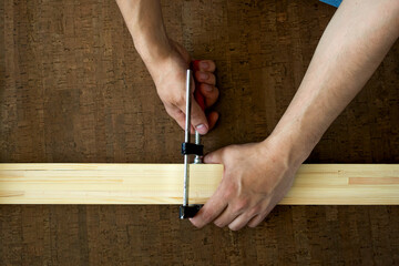 Men's hands fasten the clamp to the wooden rails, making a measurement before cutting. Repair concept