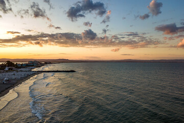 Sea surface with blue water waves under yellow and purple sunset sky.