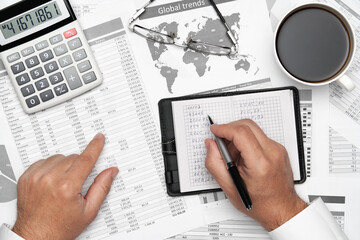 Top view of businessman working with financial statements. Modern black office desk with notebook, pencil and a lot of things. Flat lay table layout.