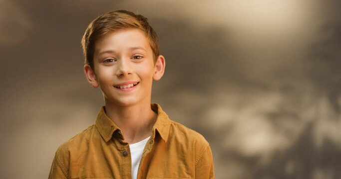 Portrait shot of Caucasian teen cute small boy looking at camera and smiling cheerfully. Close up of face of little teenage smiled schoolboy.