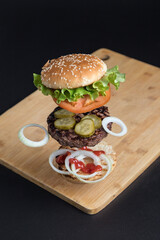 Delicious Burger with floating ingredients on the background of a wooden table