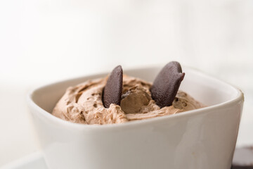 Chocolate mousse in a bowl against white background