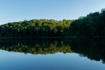 Fototapeta na wymiar Calm lake surrounded by trees at sunset