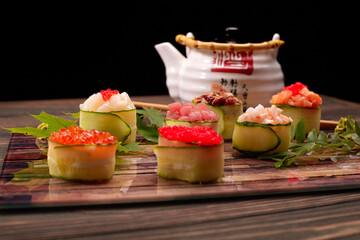 Gunkan maki in a cucumber, with caviar,tuna. scallop, eel, shrimp, eel and salmon, on a wooden board, with maple and acacia leaves, with shallow depth of field
