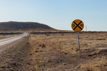 Railroad crossing sign on lonely country road in the desert or prairie