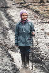 Concept - happy childhood. Little girl plays in swamp, children's fun, dirty and wet shoes