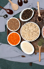 Various beans in white plates on a wooden board