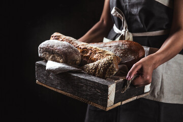 Bread in an old wooden box in the hands of a baker. Homemade pastries, rural style