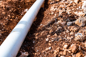 PVC pipe in dirt trench outdoors for plumbing water drainage installation. Underground irrigation system.