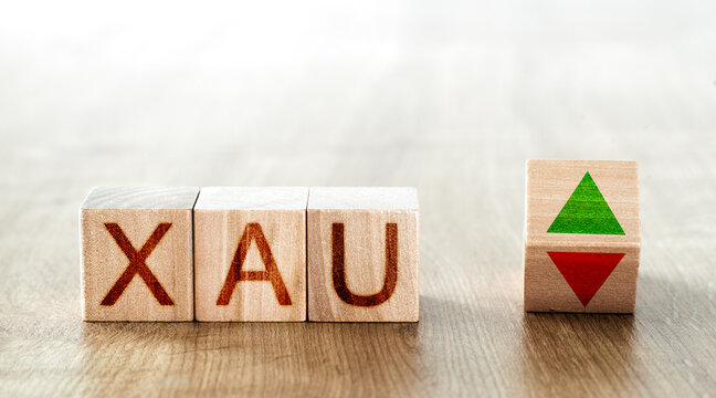 wooden blocks with the inscription xau and a block symbolizing the rise and fall of financial markets