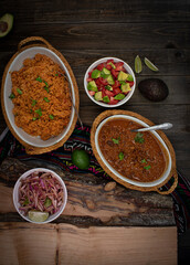 Vegan mexican rice, vegan chili, pickled onion and avocado tomato salad on wooden table, copy space