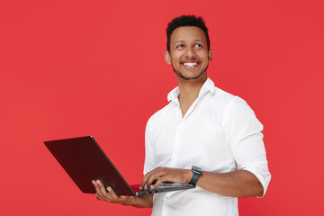 Smiling african american young man holding notebook over red background.