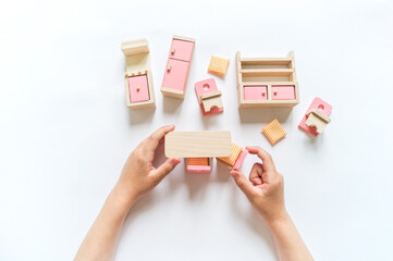 Montessori material. Wooden furniture for the doll house. Hands of a child. Eco friendly