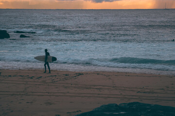 Fototapeta na wymiar silhouette of surfer walking along the beach 