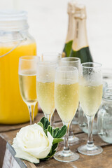 Champagne sparkling wine bottle and glasses at outdoors wedding catering event pouring into the glass and holding hand.Party and celebration.