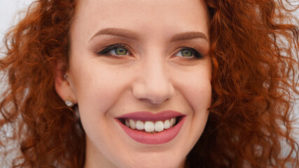 Closeup portrait on a whitish background beautiful girl with perfect teeth smiling, happy redhead...