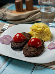 Meat cotlets with mashed potato and tomatoes in white plate