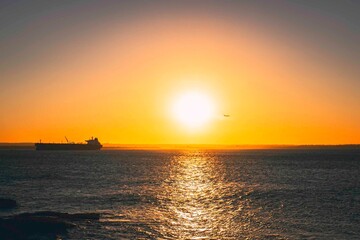 Fototapeta na wymiar orange sunset over the ports with cargo ship coming into port 
