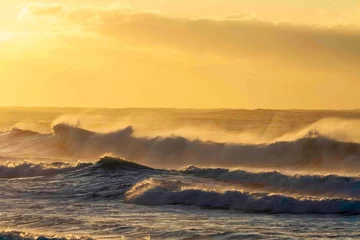 Fotobehang Oranje sunrise over the beach, bright yellow sun lighting up the waves  © Em Neems Photography