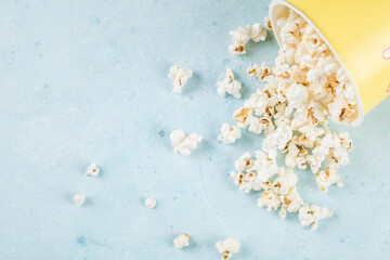 Fresh popcorns spread over the blue table out of the box