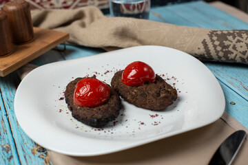 Meat cotlets with tomatoes in a white plate.
