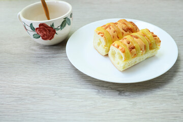 Loaves of cheese bread and coffee poured on wooden table 