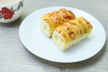 Close view of loaves of cheese bread on white plate on wooden table 